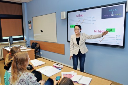In the foreground, the lecturer with an interactive monitor in the background during the lesson. Click to zoom the picture.